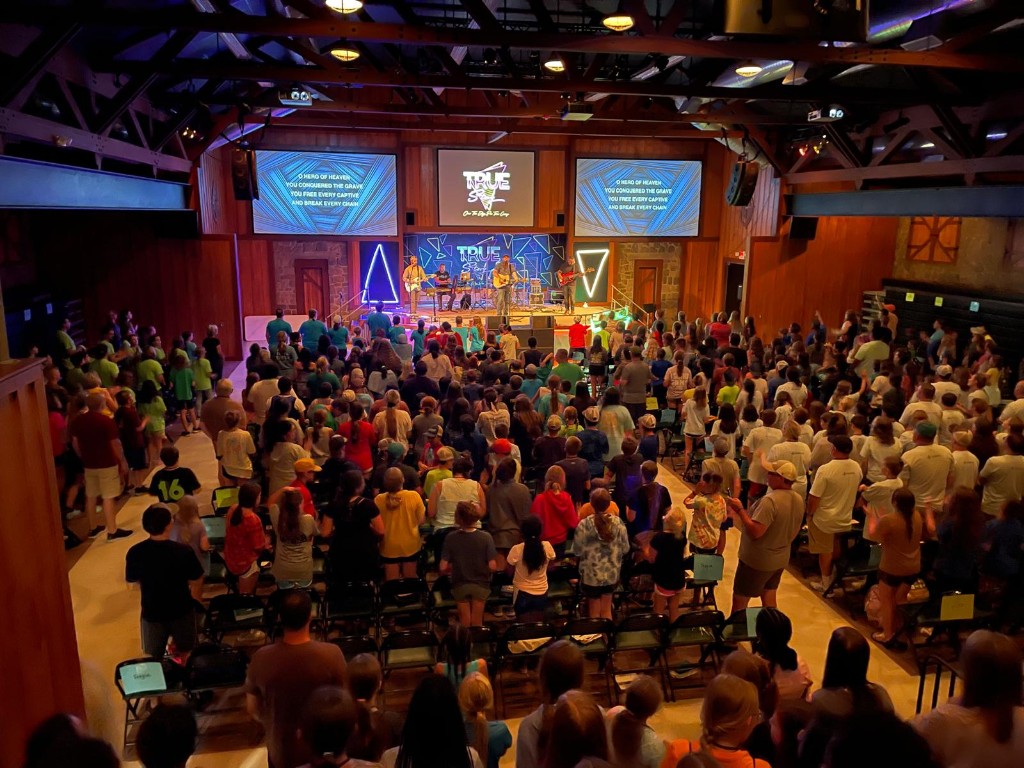 Large indoor concert and worship event with professional lighting and line-array sound.