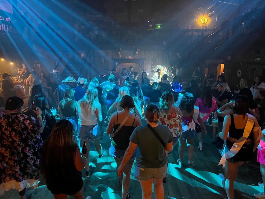 Crowded country-style dance floor with blue lights and party guests.